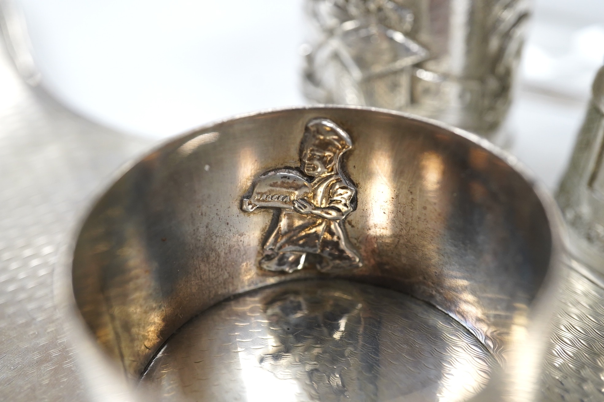 Small silver including a napkin ring, hand mirror and two mounted glass toilet jars, together with three Indian white metal condiments and a French white metal wine taster. Condition - poor to fair